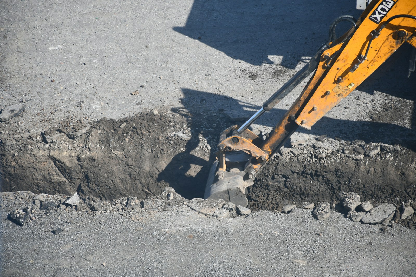Excavator digging a trench in the road